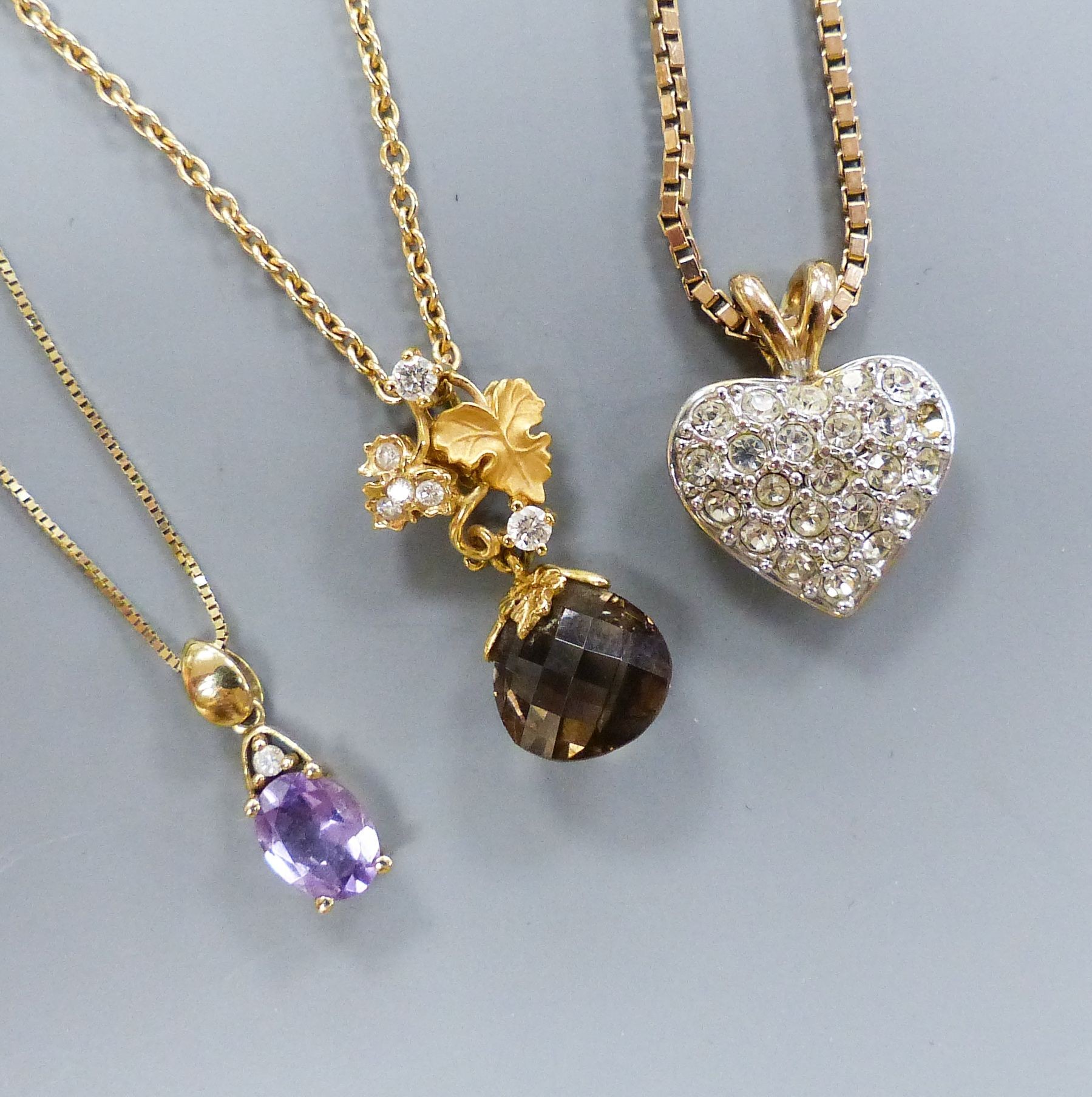 A smoky quartz pear-shaped pendant on diamond-set 'leaf' suspension and 9ct gold chain, a 9ct gold box-link chain with paste 'heart' pendant and a 9ct gold and amethyst pendant on 9ct gold fine chain.